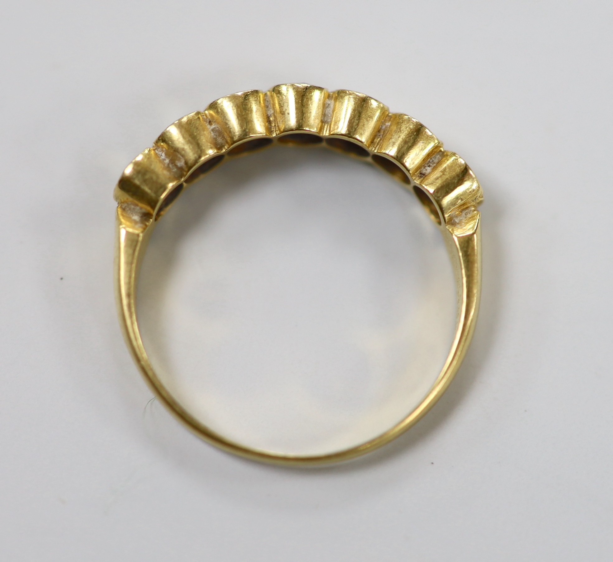 A modern 750 yellow metal and seven stone diamond set half hoop ring, size O, gross weight 3.2 grams.